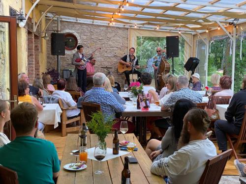 um grupo de pessoas sentadas num restaurante com músicos em Divas Upes em Koknese