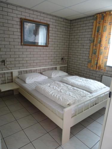un letto bianco in una stanza con un muro di mattoni di Kustverhuur, Park Schoneveld, Strandparel 365 a Breskens
