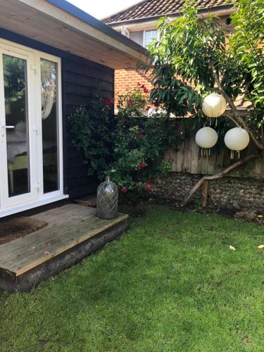 a porch of a house with a door and a yard at Pretty self-contained garden room in Sheringham
