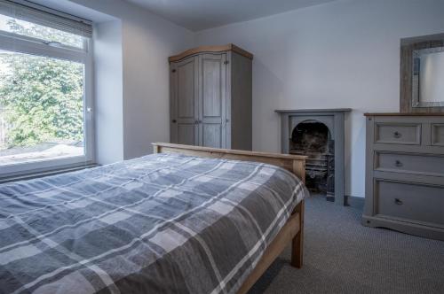 ein Schlafzimmer mit einem Bett, einer Kommode und einem Kamin in der Unterkunft Cambrian Cottage - 3 Bedroom Cottage - Tenby in Tenby