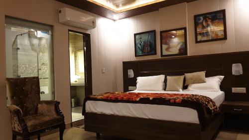 a bedroom with a large bed and a chair at Maple Leaf Hotel in Kharar