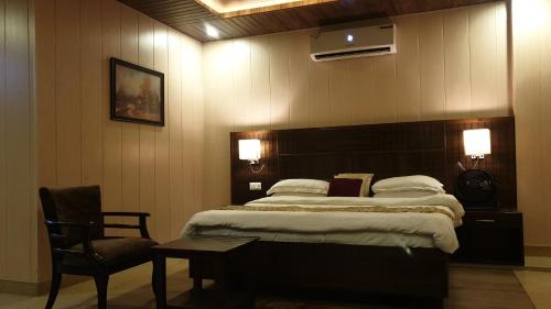 a bedroom with a bed and a table and a chair at Maple Leaf Hotel in Kharar