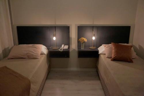 a bedroom with two beds and two lights on the wall at RecoBerta Studio. Vivir Recoleta!! in Buenos Aires