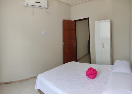 einen rosa Bogen auf einem weißen Bett im Schlafzimmer in der Unterkunft Casa do Lamarques in Piranhas
