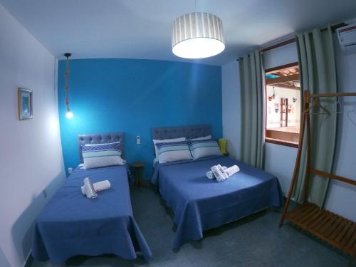 a blue room with two beds and a window at Pousada Melodia do Mar in Cabo Frio