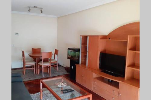 ein Wohnzimmer mit einem TV und einem Esstisch in der Unterkunft Piso Vilavella in Redondela