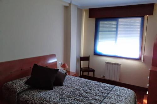 a bedroom with a bed with a large window at Piso Vilavella in Redondela