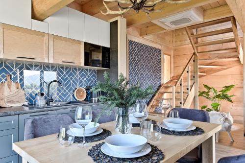 a kitchen with a wooden table with plates and wine glasses at Osada Bachledzki Wierch Odkryj Zakopane in Zakopane