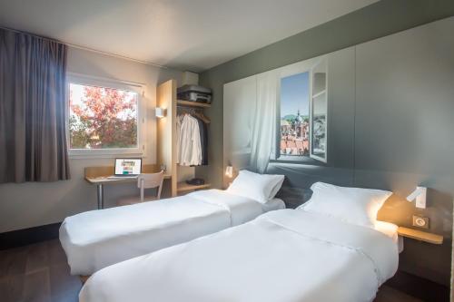昆西的住宿－B&B HOTEL Douai Parc Des Expos Cuincy，酒店客房设有两张床和窗户。