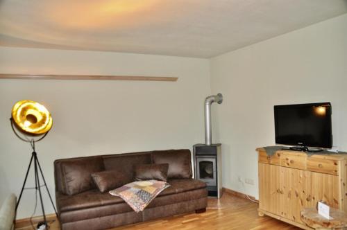 a living room with a brown couch and a flat screen tv at Sonnenapartment in Going