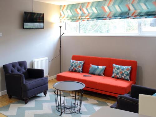 ダンガノンにあるKC Accommodationsのリビングルーム(赤いソファ、椅子2脚付)