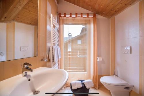 a bathroom with a sink and a toilet and a window at Villa Anita San Vigilio di Marebbe in San Vigilio Di Marebbe