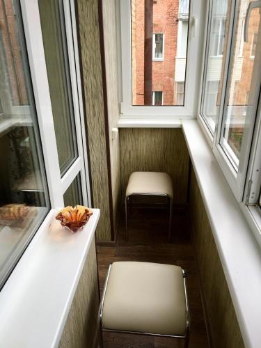 einen kleinen Balkon mit einem Stuhl und zwei Fenstern in der Unterkunft Апартаменти in Tschernihiw