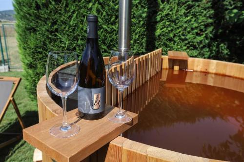 a bottle of wine and two wine glasses on a wooden table at Healthy House Glamping in Koper