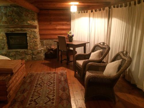 a living room with two chairs and a table with a fireplace at Log Cabin - Monte Verde in Camanducaia