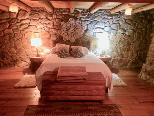 a bedroom with a bed and a stone wall at Log Cabin - Monte Verde in Camanducaia