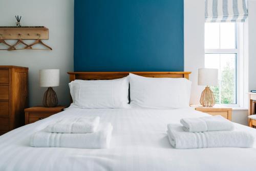 a bedroom with a white bed with two towels on it at Bryn Berwyn Country House Tresaith in Penbryn