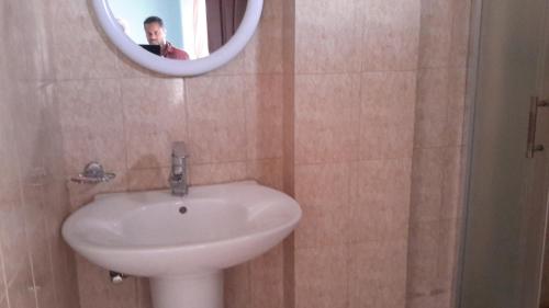 un uomo che scatta una foto di un lavandino bianco in bagno di Pure Pension ad Addis Abeba