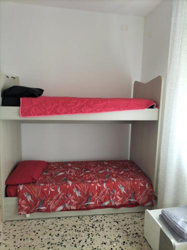 a bedroom with two bunk beds with red sheets at NOEMI & JULIENNE in Spineda