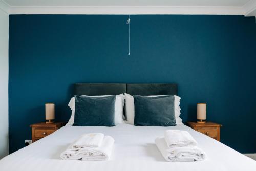 a bed with towels on it with a blue wall at Bryn Berwyn Country House Tresaith in Penbryn