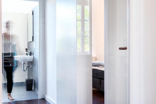 d'une salle de bains avec une porte s'ouvrant sur une salle de bains pourvue d'un lavabo. dans l'établissement Insel-Apartment im Herrenhaus Rheinblick, à Xanten
