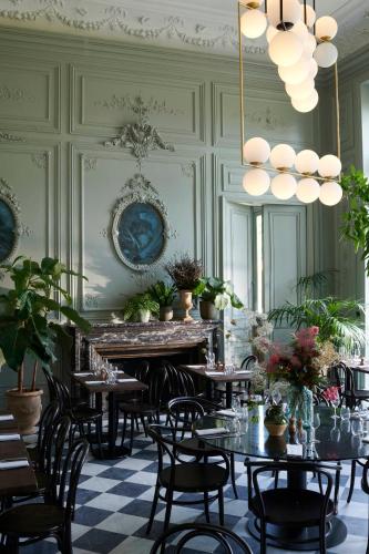 a dining room with tables and chairs and a chandelier at Maison du Val - Les Maisons de Campagne in Saint-Germain-en-Laye