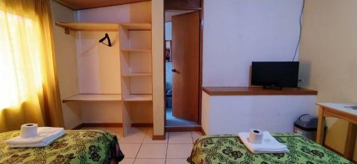 Habitación pequeña con 2 camas y TV. en HOTEL DULZURA, en Caraz