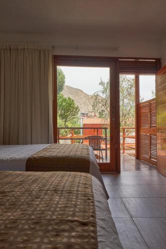 a bedroom with two beds and a balcony with a view at El Molino Hotel y Restaurant in Lunahuaná