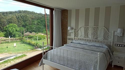 a bedroom with a bed and a large window at Villageermis - Casa Rural in Moraña