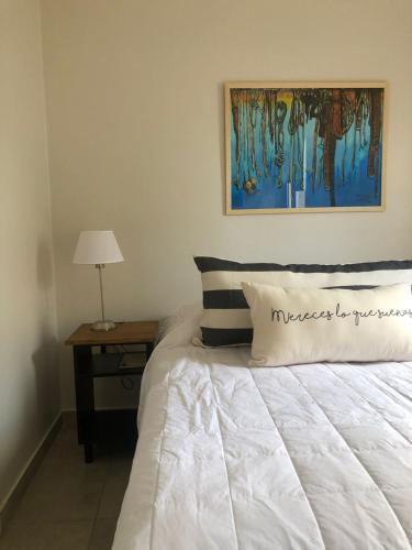 a bedroom with a white bed with a table and a painting at Deptos Tuc in San Miguel de Tucumán