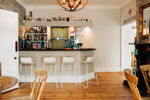 a kitchen with a bar with white stools at Bryn Berwyn Country House Tresaith in Penbryn
