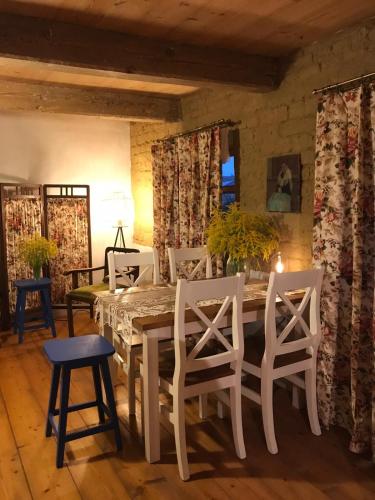 a dining room with a white table and chairs at Chałupa łowicka z XIX wieku in Zduny