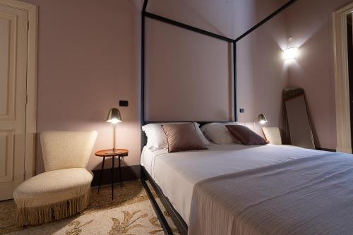 a bedroom with a large bed and a chair at Palazzo Francesco Grassi in Aradeo