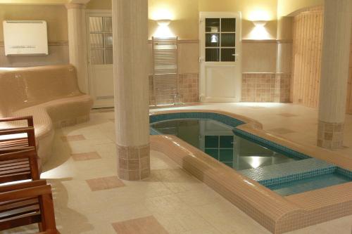 a large swimming pool in a hotel room with a lobby at Öreg Miskolcz Hotel in Miskolc