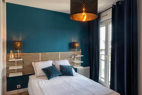 - une chambre avec des murs bleus et un lit avec des oreillers dans l'établissement THIERS #16 - Appart avec terrasse - 1 Chambre, à Brive-la-Gaillarde
