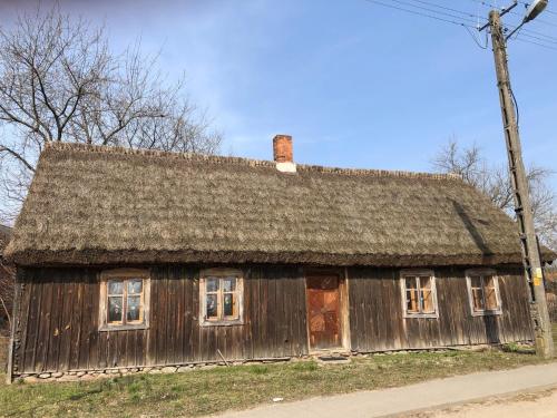 una antigua casa de madera con techo en Chałupa łowicka z XIX wieku, en Zduny