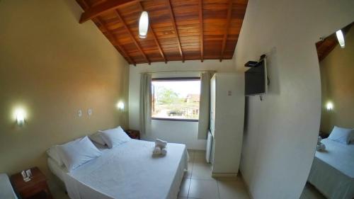 a bedroom with a white bed and a window at Pousada Villa Maritima in Trindade