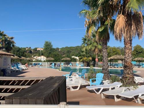 a pool with chaise lounge chairs and palm trees at Camping Le Montourey in Fréjus