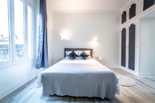een witte slaapkamer met een groot bed met 2 kussens bij VOLTAIRE #2 - Studio - 1 chambre in Brive-la-Gaillarde