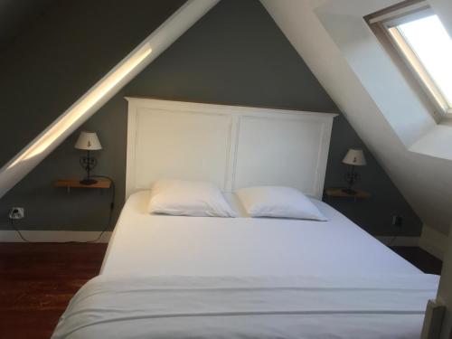 een slaapkamer met een groot wit bed met 2 kussens bij Gîte de la Doucette in Paimpont