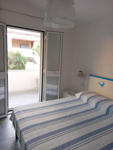 a bedroom with a bed with a blue and white striped blanket at Casa Maria in Siniscola