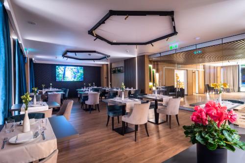a dining room with tables and chairs and flowers at Aparthotel NOX in Cluj-Napoca