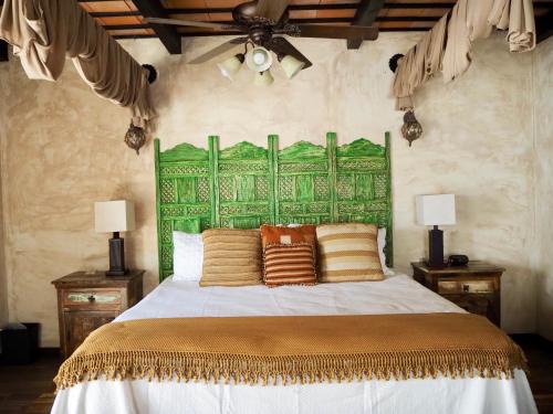 a bedroom with a large bed with a green headboard at Hotel Casa Madeleine B&B & Spa in Antigua Guatemala