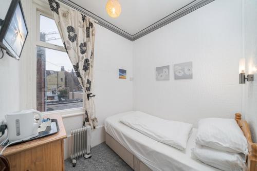 a small bedroom with a bed and a window at Deneside Guest House in Blackpool