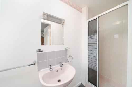 a white bathroom with a sink and a shower at Deneside Guest House in Blackpool