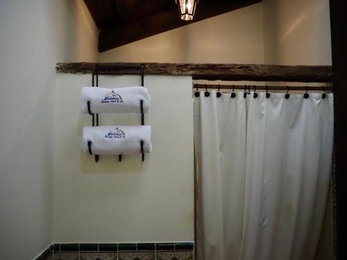 y baño con toallas sobre una cortina de ducha. en Hotel Casa Madeleine B&B & Spa, en Antigua Guatemala