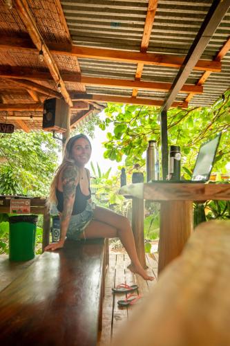 a woman sitting on a table with a laptop at Akih Pods Hostel in Santa Teresa Beach