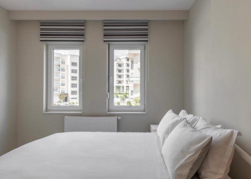 1 dormitorio con 1 cama blanca y 2 ventanas en BLERI Apartment, 2 Bedroom, Free parking, en Pristina