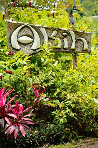 a sign in a garden with flowers and plants at Akih Pods Hostel in Santa Teresa Beach