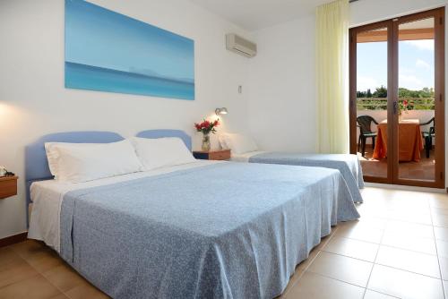 a bedroom with two beds and a balcony at Hotel Oasis in Alghero
